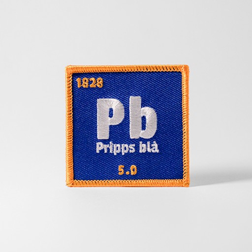 Blått tygmärke med texten "Pb"